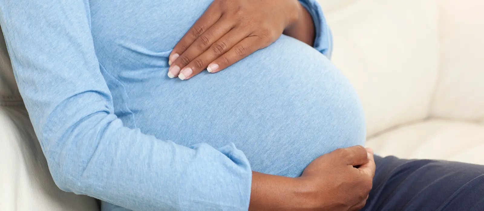 Eine schwangere Frau hält sich ihre Hände an den Bauch