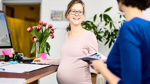 Eine schwangere Frau nimmt eine Broschüre entgegen
