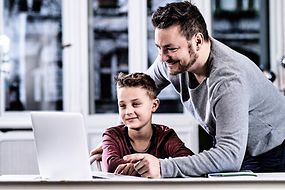 Ein Vater unterstützt seinen Sohn am Laptop