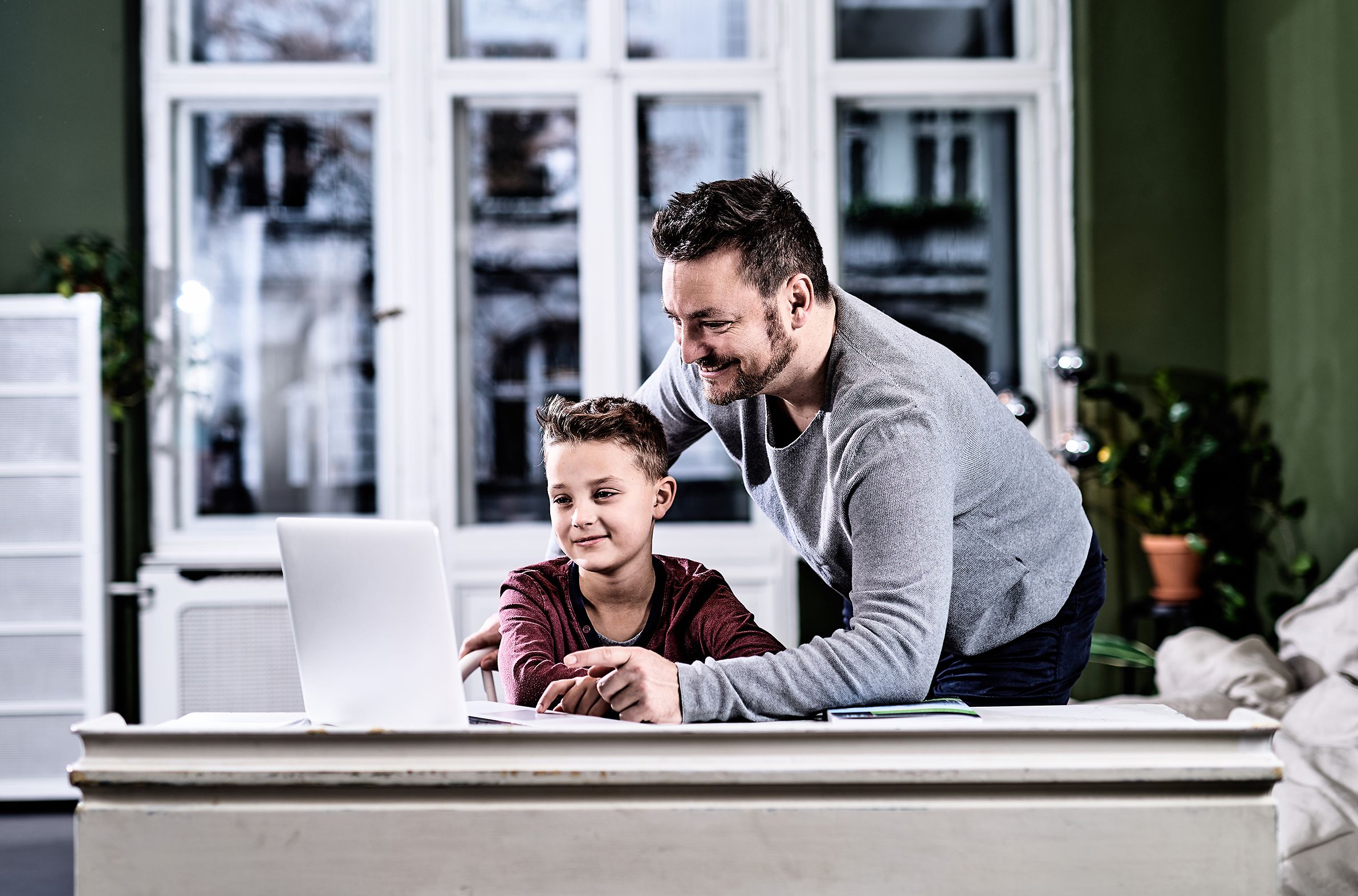 Ein Vater unterstützt seinen Sohn am Laptop