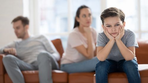 Ein Junge sitzt frustriert vor seinen Eltern