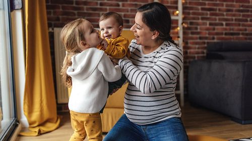 Eine Mutter spielt mit ihrem Kleinkind und ihrem Baby