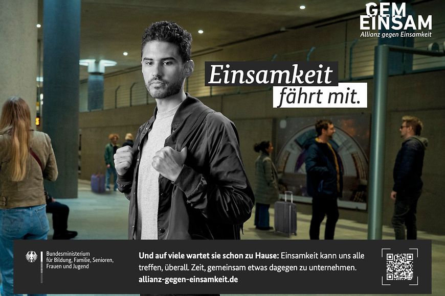 Junger Mann steht alleine an einem Bahnhof.