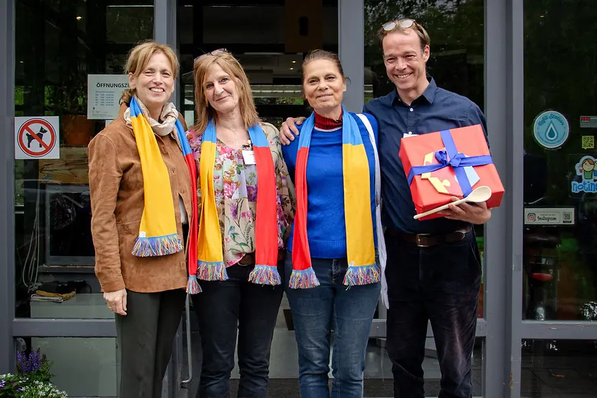 Bundesministerin Karin Prien mit Sarah Wiener und zwei weiteren menschen vor der Eingangstür eines Mehrgenerationenhauses