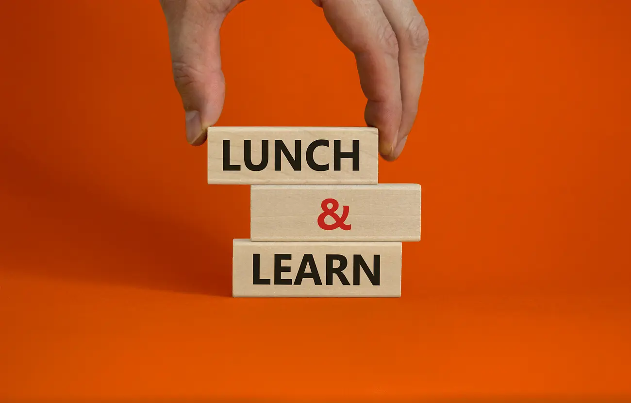 3 Holzwürfel auf orangem Hintergrund mit der Aufschrift Lunch & Learn