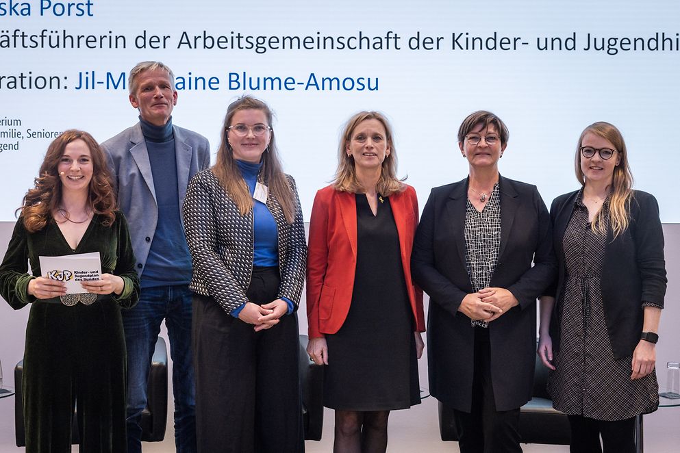 Karin Prien und andere auf Podium vor Leinwand