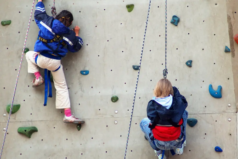 Ein Mädchen klettert auf einer Boulder-Wand 