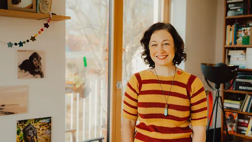 Eine junge Frau mit buntem T-Short vor Fenster und Regal