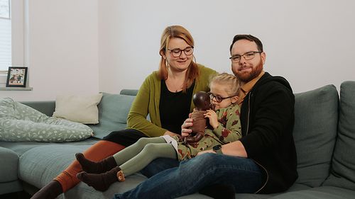 Ein junges Paar mit Tochter auf der Couch