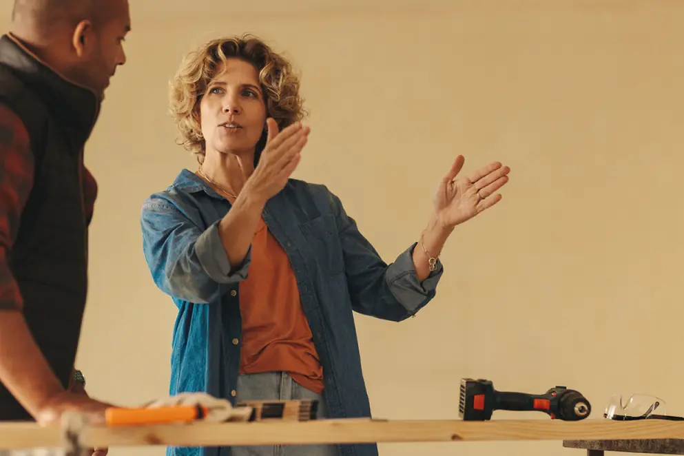 Eine Frau schaut zu einem Mann und erklärt ihm etwas, dabei hebt sie ihre Hände