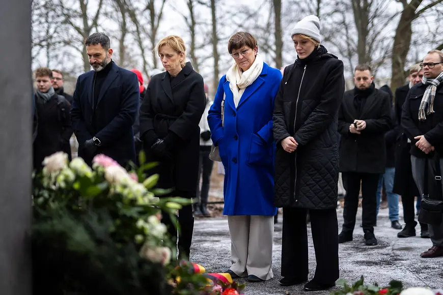 Karin Prien und weitere Personen stehen vor dem Denkmal für die im Nationalsozialismus verfolgten Homosexuellen
