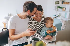 Junge Familie in einer Wohnung am Tisch mit einem Laptop