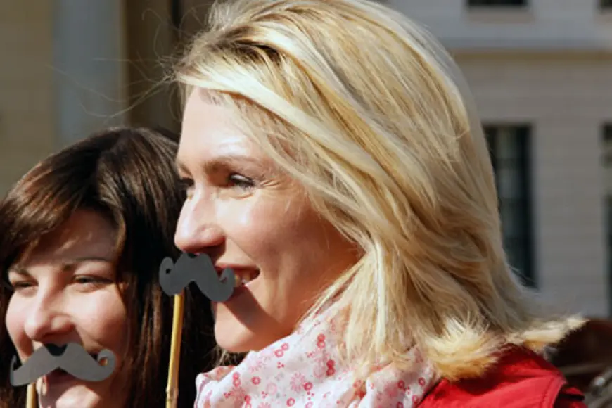 Manuela Schwesig hält sich einen Papier-Schnurrbart an